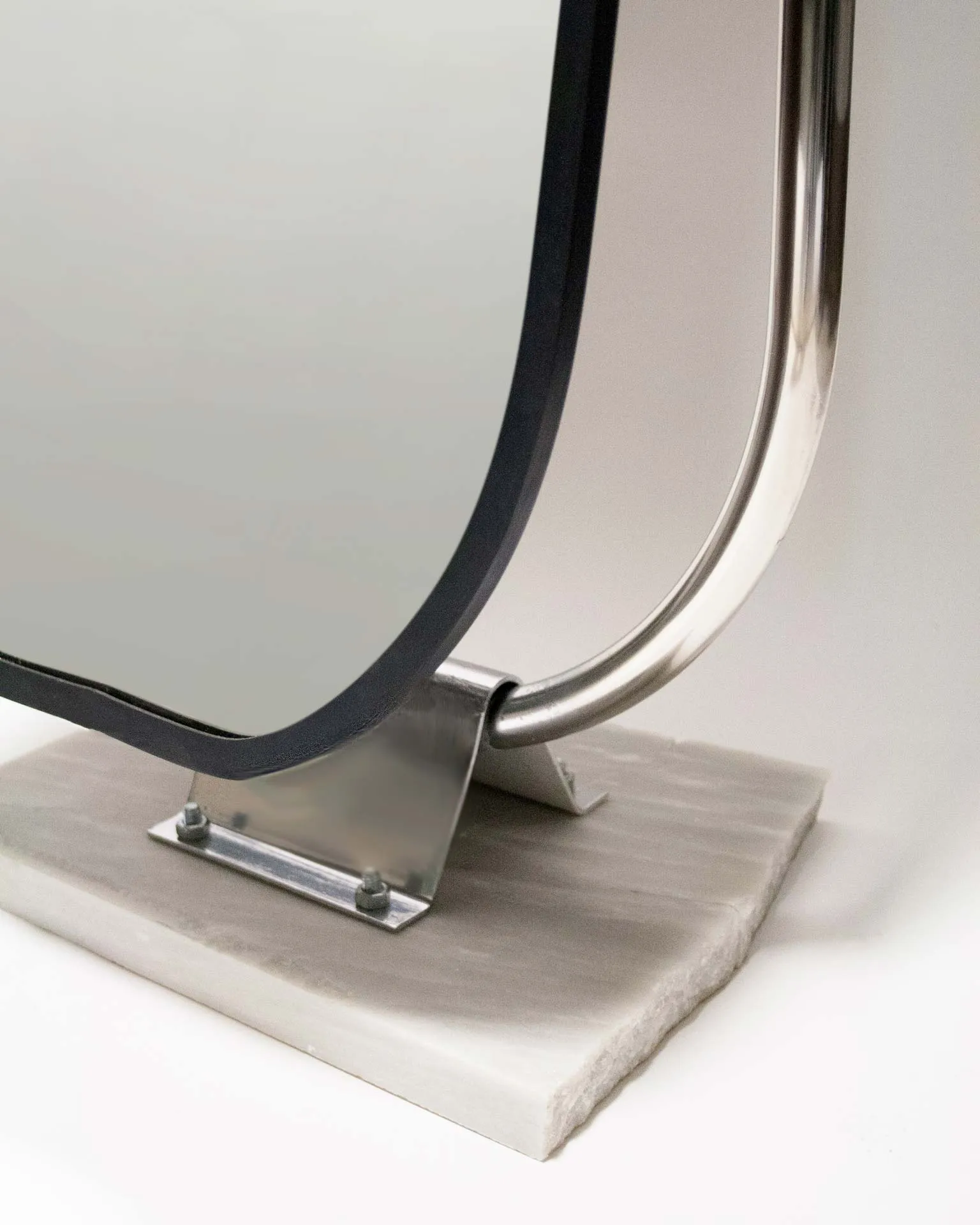 A mirror created by Jannis Schäfer Studio, made from upcycled theft detectors and a reclaimed marble tabletop. The design features a tall, narrow, swingable mirror framed in a chrome structure with a marble base. This object, titled 'Stealing Beauty,' is part of a series of recycled and transformed designs.