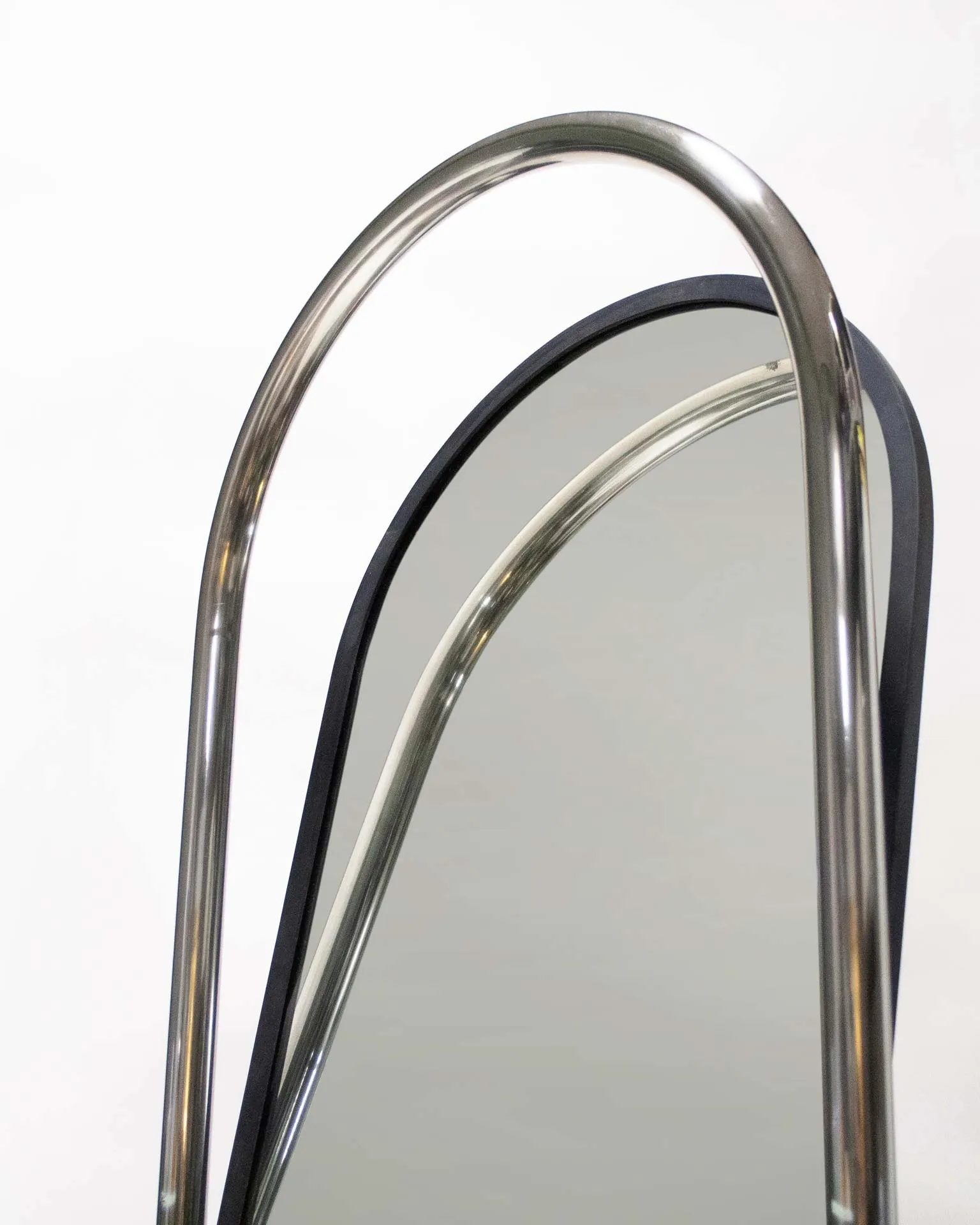 A mirror created by Jannis Schäfer Studio, made from upcycled theft detectors and a reclaimed marble tabletop. The design features a tall, narrow, swingable mirror framed in a chrome structure with a marble base. This object, titled 'Stealing Beauty,' is part of a series of recycled and transformed designs.