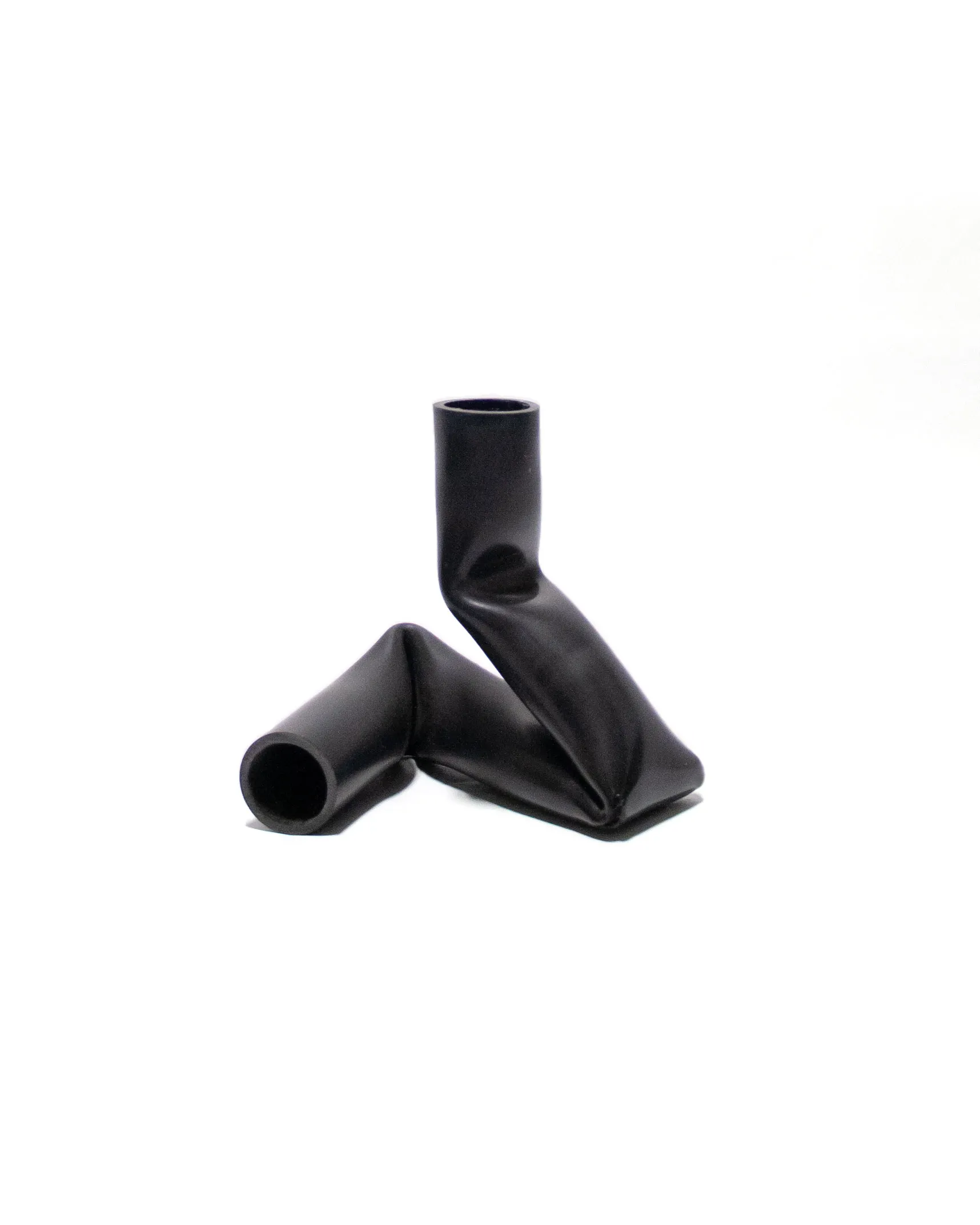 A candle holder created by Jannis Schäfer Studio, made from upcycled PVC tube. The design features a unique, twisted form with two cylindrical openings for candles. This transformed and reclaimed material piece is part of a series of derivative designs.