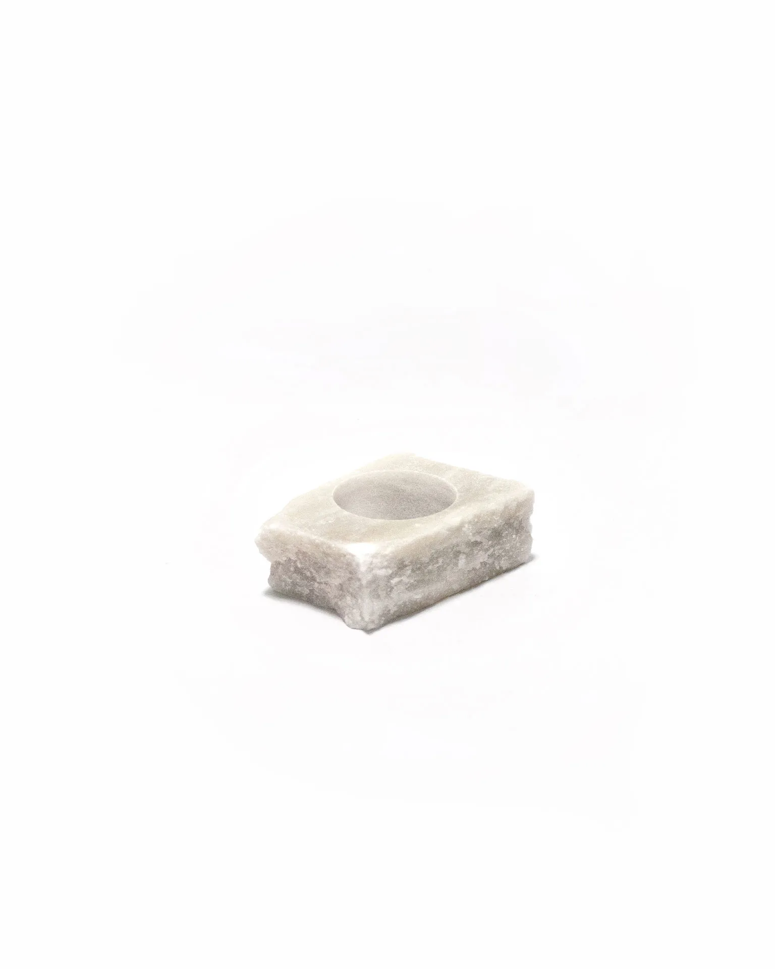 The 'Lithic Egg Cup,' created by Studio Jannis Schäfer, is made from a reclaimed marble tabletop. The design features a brown egg sitting on a small, rectangular marble base. This upcycled, recycled, and transformed piece is part of a series of derivative designs.