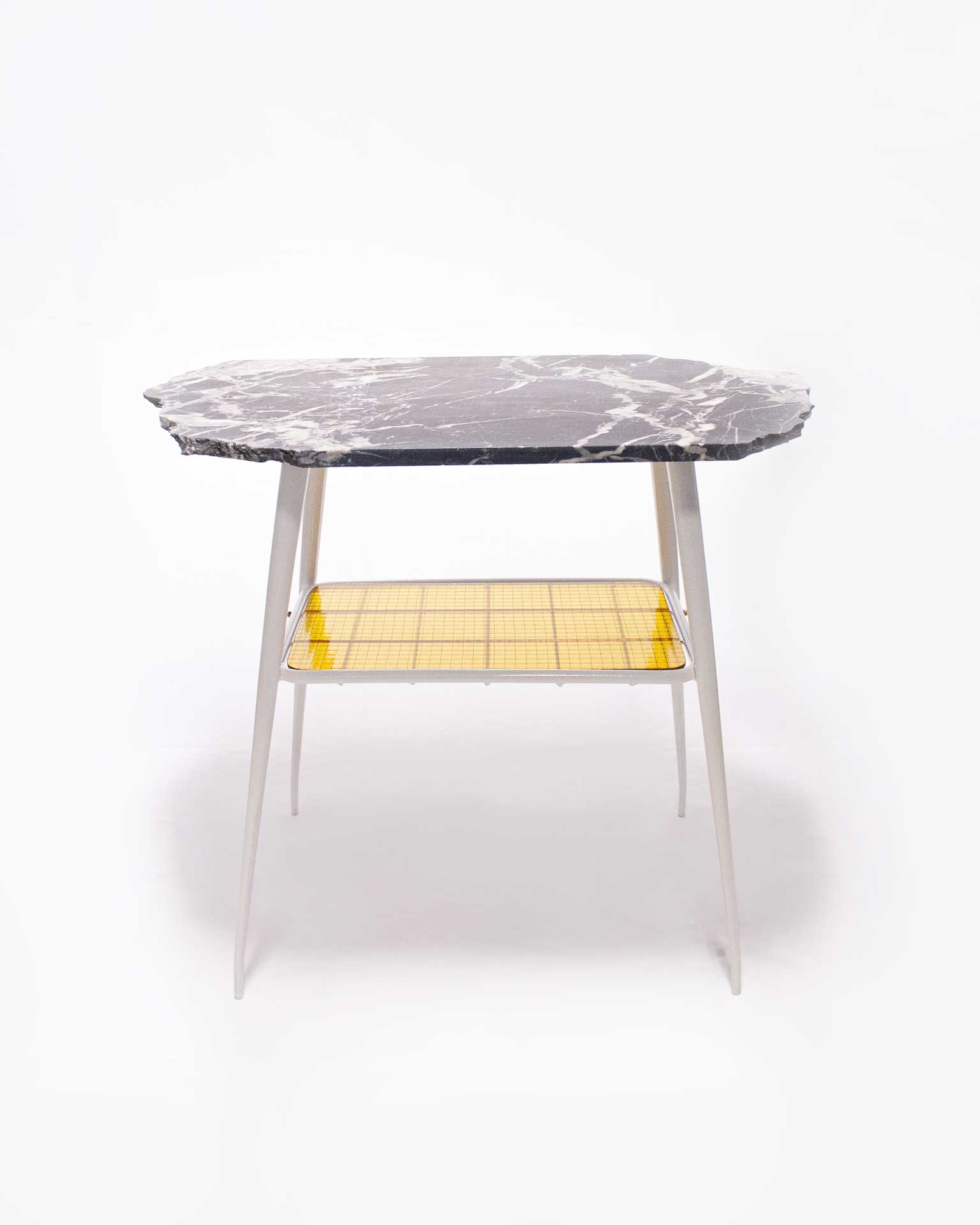 "The 'Lithic Side Table,' created by Jannis Schäfer Studio, is made from reclaimed black marble (nero Marquina) and wired glass, set on an unwanted table frame. This upcycled, recycled, and transformed piece is part of a series of derivative designs. The table features a black marble top with white veining and a yellow wired glass shelf beneath."